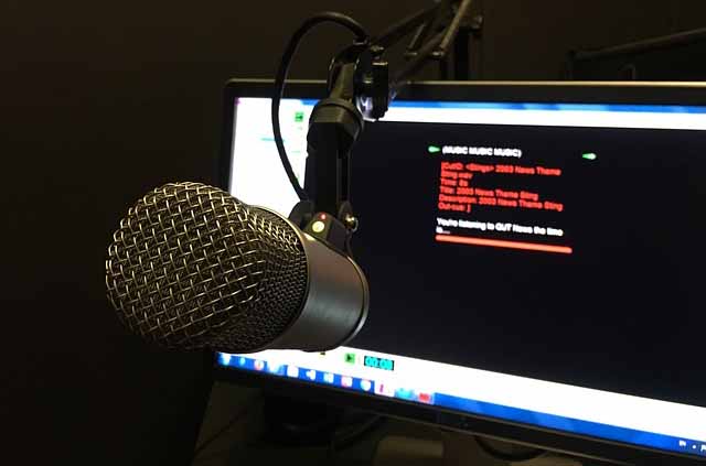 A picture of a radio station microphone in front a computer screen